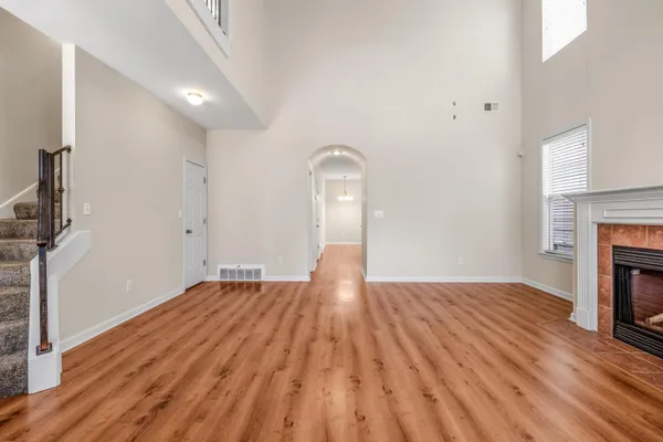 a view of an empty room with wooden floor fireplace and a window