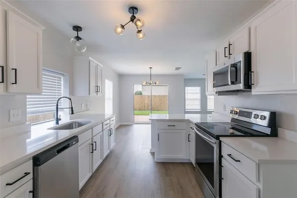 a kitchen with stainless steel appliances a sink dishwasher a stove a microwave oven with cabinets