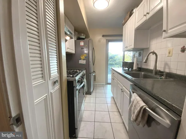 a kitchen with a sink stainless steel appliances a counter space and a window