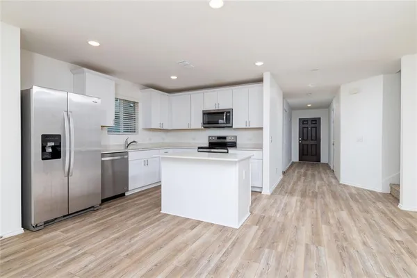 a kitchen with granite countertop a refrigerator stove top oven and sink
