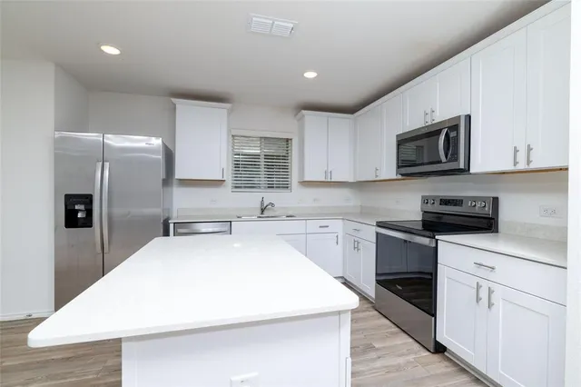 a kitchen with stainless steel appliances a refrigerator microwave stove sink and cabinets
