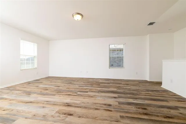 a view of an empty room with window and wooden floor