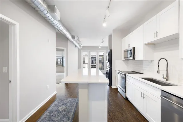 a large white kitchen with kitchen island a sink stainless steel appliances and cabinets