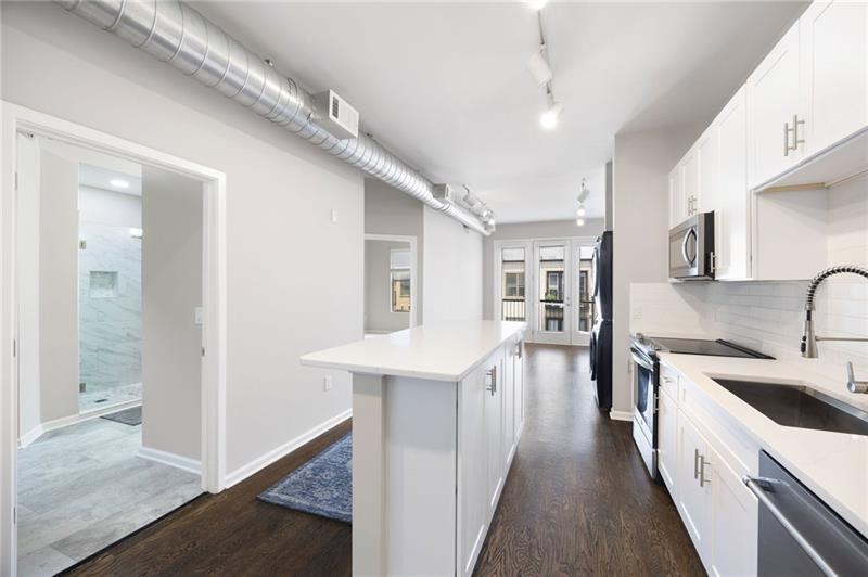 5300 Peachtree Road, Unit 3207 Chamblee, GA 30341 - Photo 6 of 25 a kitchen with stainless steel appliances a sink dishwasher a stove a refrigerator and cabinets with wooden floor