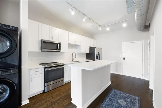 a kitchen with stainless steel appliances a stove a sink a microwave a refrigerator and cabinets