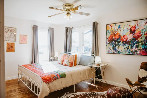 a bedroom with a bed a painting on the wall and a large window