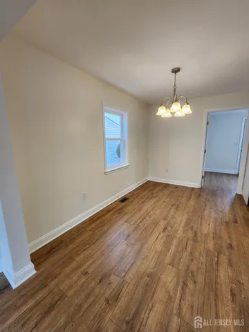 an empty room with wooden floor and chandelier