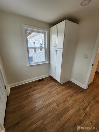 an empty room with wooden floor cabinet and windows