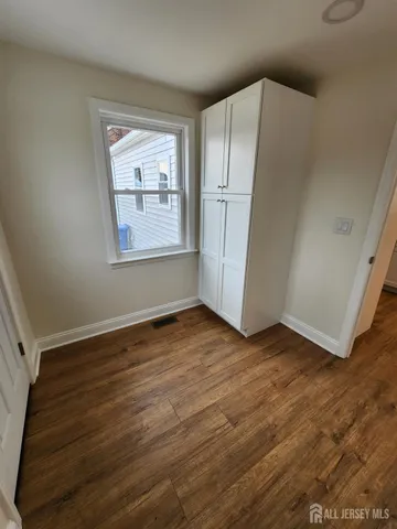 an empty room with wooden floor cabinet and windows