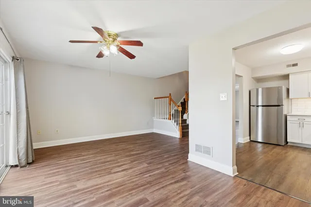 a view of empty room with wooden floor and ceiling fan