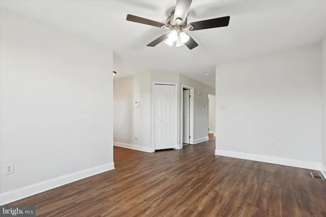an empty room with wooden floor fan and windows