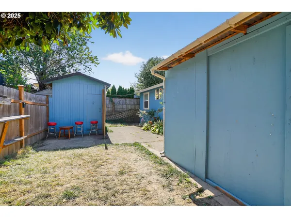 a view of backyard with wooden fence and large trees