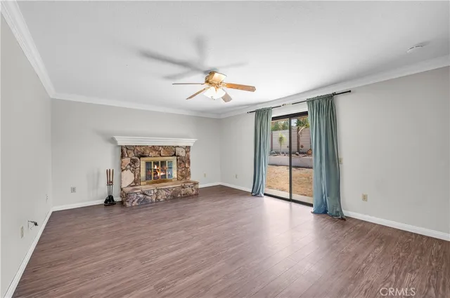 an empty room with wooden floor and a ceiling fan