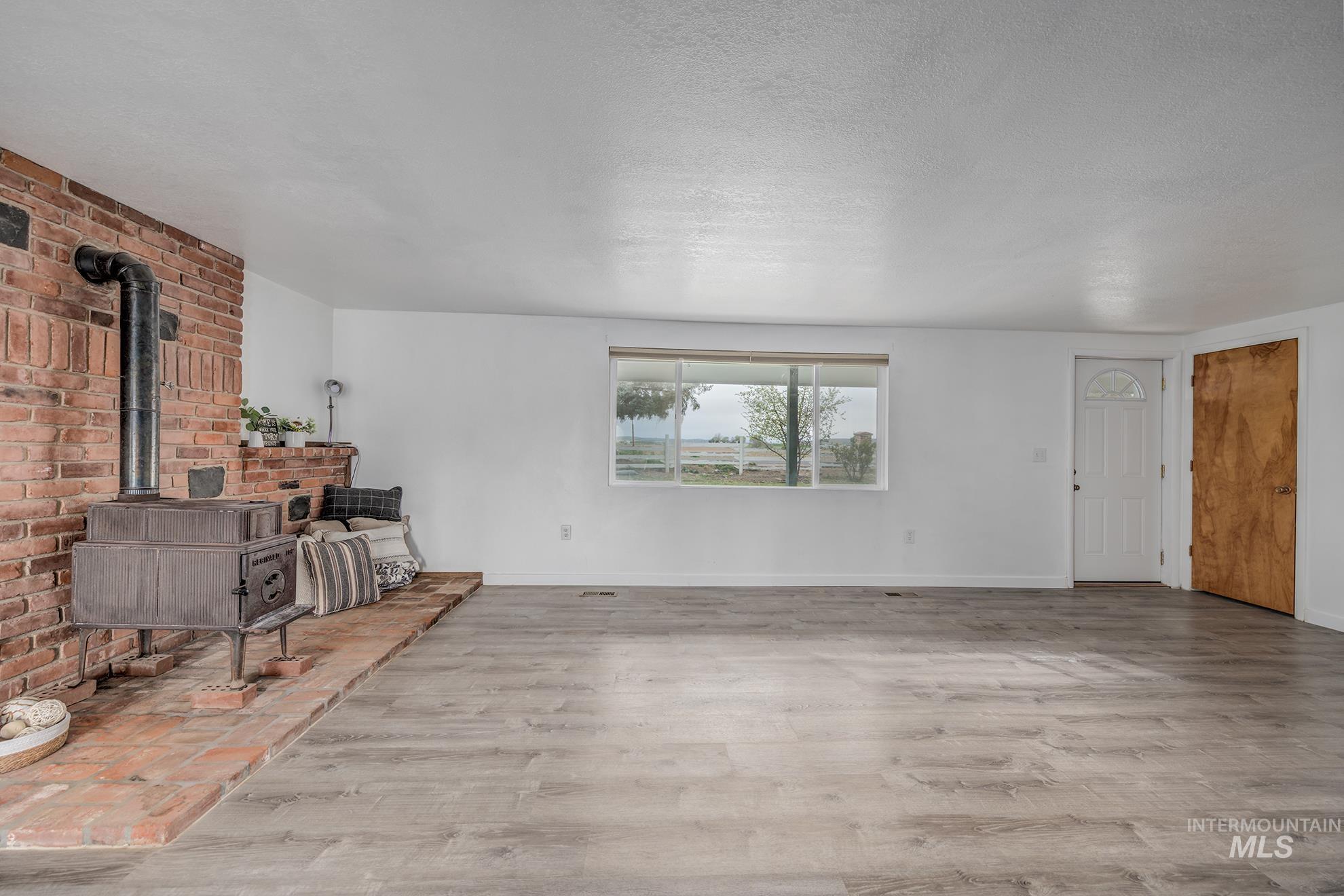 4484 Community Road Ontario, OR 97914 - Photo 8 of 35 Living area featuring light wood-type flooring, a wood stove, and a textured ceiling