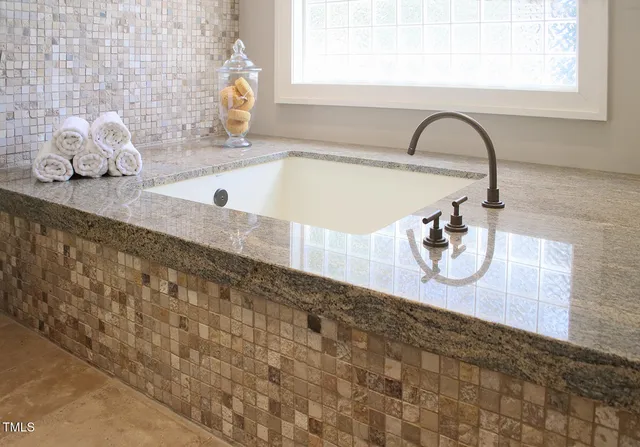 a bathroom with a granite countertop sink a mirror and shower