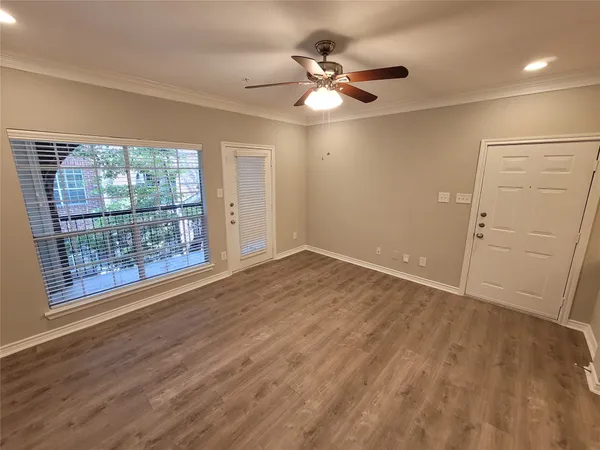 an empty room with wooden floor fan and windows