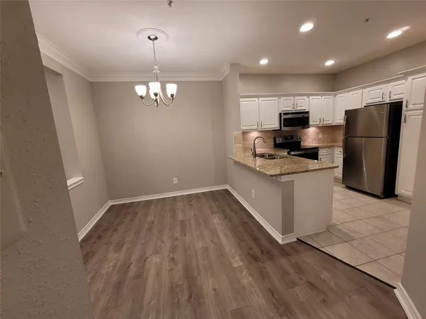 a kitchen with stainless steel appliances granite countertop a refrigerator a sink dishwasher a stove with white cabinets and wooden floor