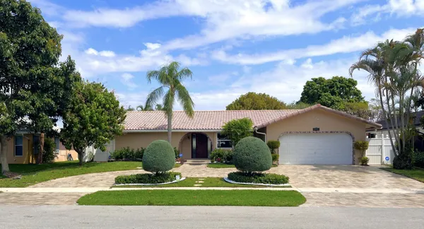 a view of a white house with a yard and potted plants