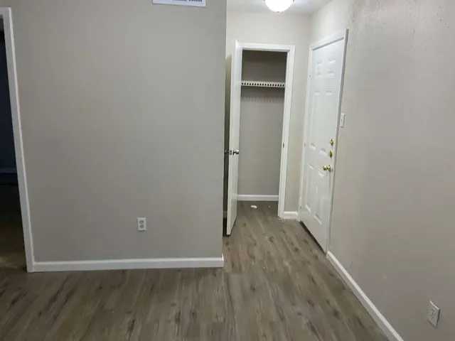 a view of an empty room with wooden floor and closet