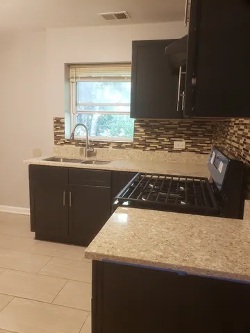 a kitchen with a sink a stove and wooden cabinets