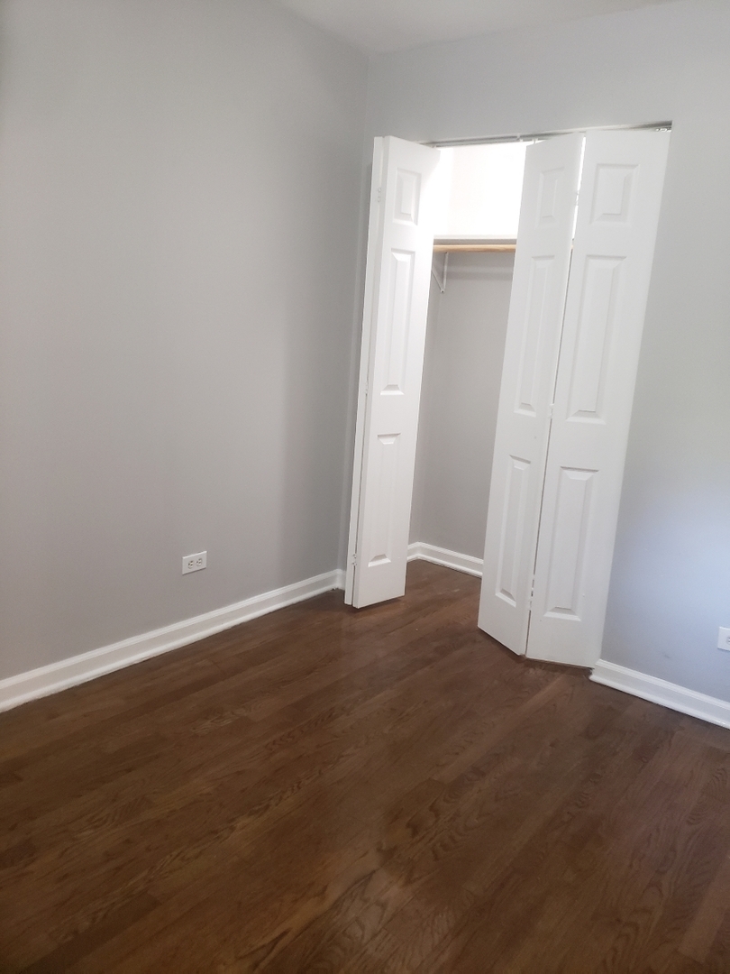 1061 East 80th Street, Unit 2N Chicago, IL 60619 - Photo 6 of 8 an empty room with wooden floor and closet