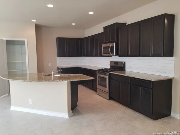 a kitchen with kitchen island granite countertop a sink dishwasher stove and cabinets