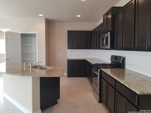 a kitchen with granite countertop stainless steel appliances a sink stove and refrigerator