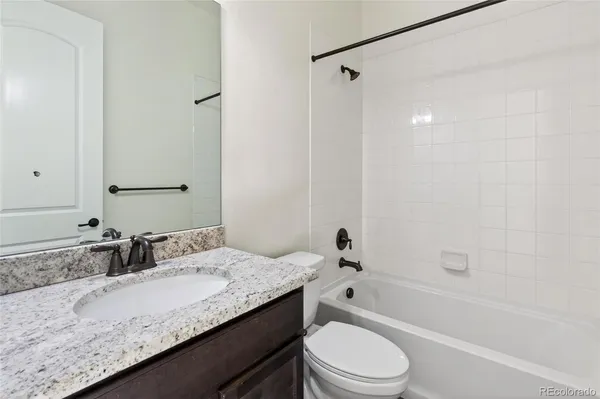 a bathroom with a granite countertop sink a toilet and shower