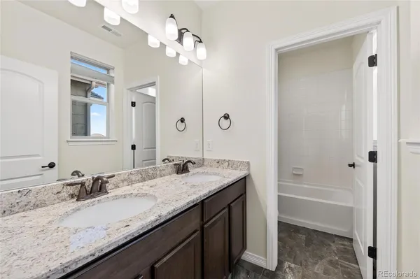 a bathroom with a granite countertop sink a mirror and a bathtub