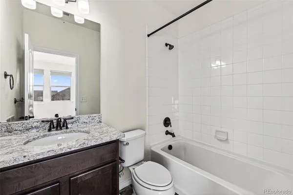 a bathroom with a granite countertop sink a toilet a mirror a bathtub and shower