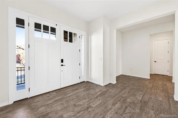 a view of an empty room with wooden floor and windows