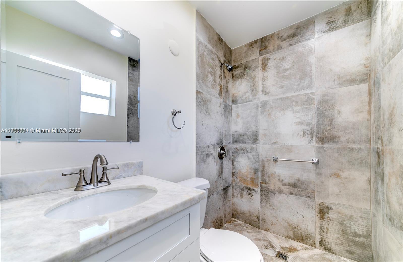 7975 Crespi Boulevard, Unit 1 Miami Beach, FL 33141 - Photo 15 of 21 a bathroom with a sink toilet a mirror and shower