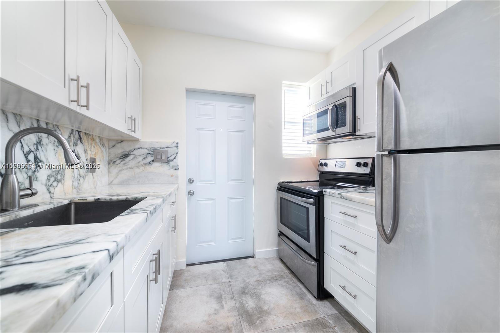 7975 Crespi Boulevard, Unit 1 Miami Beach, FL 33141 - Photo 6 of 21 a kitchen with stainless steel appliances granite countertop a refrigerator and a sink