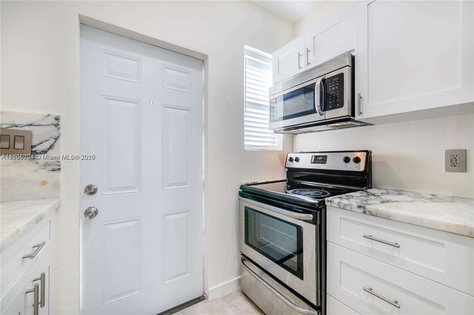 7975 Crespi Boulevard, Unit 1 Miami Beach, FL 33141 - Photo 8 of 21 a kitchen with a stove and microwave
