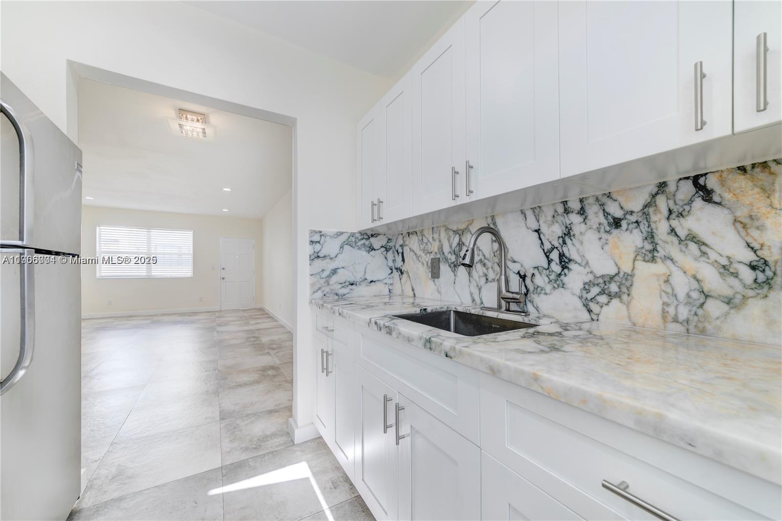 7975 Crespi Boulevard, Unit 1 Miami Beach, FL 33141 - Photo 9 of 21 a view of a kitchen with a sink and refrigerator