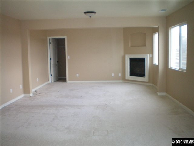 10895 Dancing Aspen Drive Reno, NV 89521 - Photo 2 of 9 an empty room with windows and fireplace