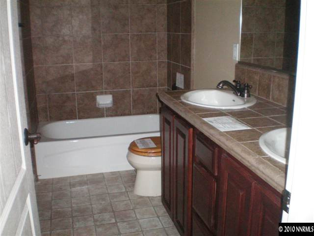 10895 Dancing Aspen Drive Reno, NV 89521 - Photo 7 of 9 a bathroom with a granite countertop sink a toilet and a mirror