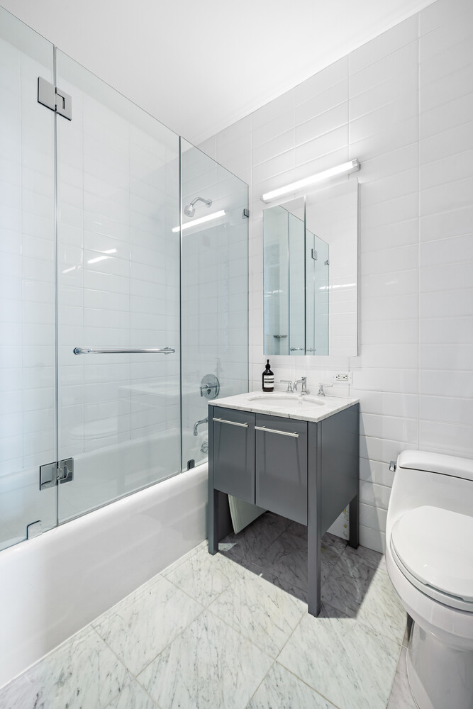 310 East 53rd Street, Unit 21C Manhattan, NY 10022 - Photo 15 of 19 a bathroom with a bathtub a sink and a toilet
