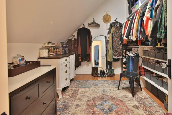 a view of a walk in closet with clothes and shoes