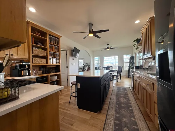 a dining hall with stainless steel appliances kitchen island granite countertop a refrigerator a stove and a sink with wooden floor
