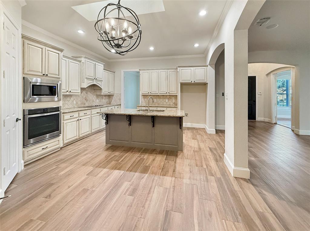 3779 Navarro Way Frisco, TX 75034 - Photo 4 of 17 a kitchen with stainless steel appliances granite countertop a stove top oven a sink dishwasher and white cabinets with wooden floor