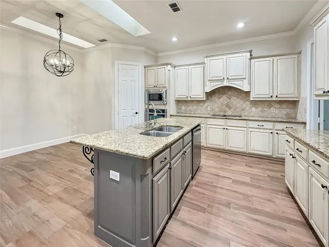 a kitchen with kitchen island granite countertop a sink and a stove top oven
