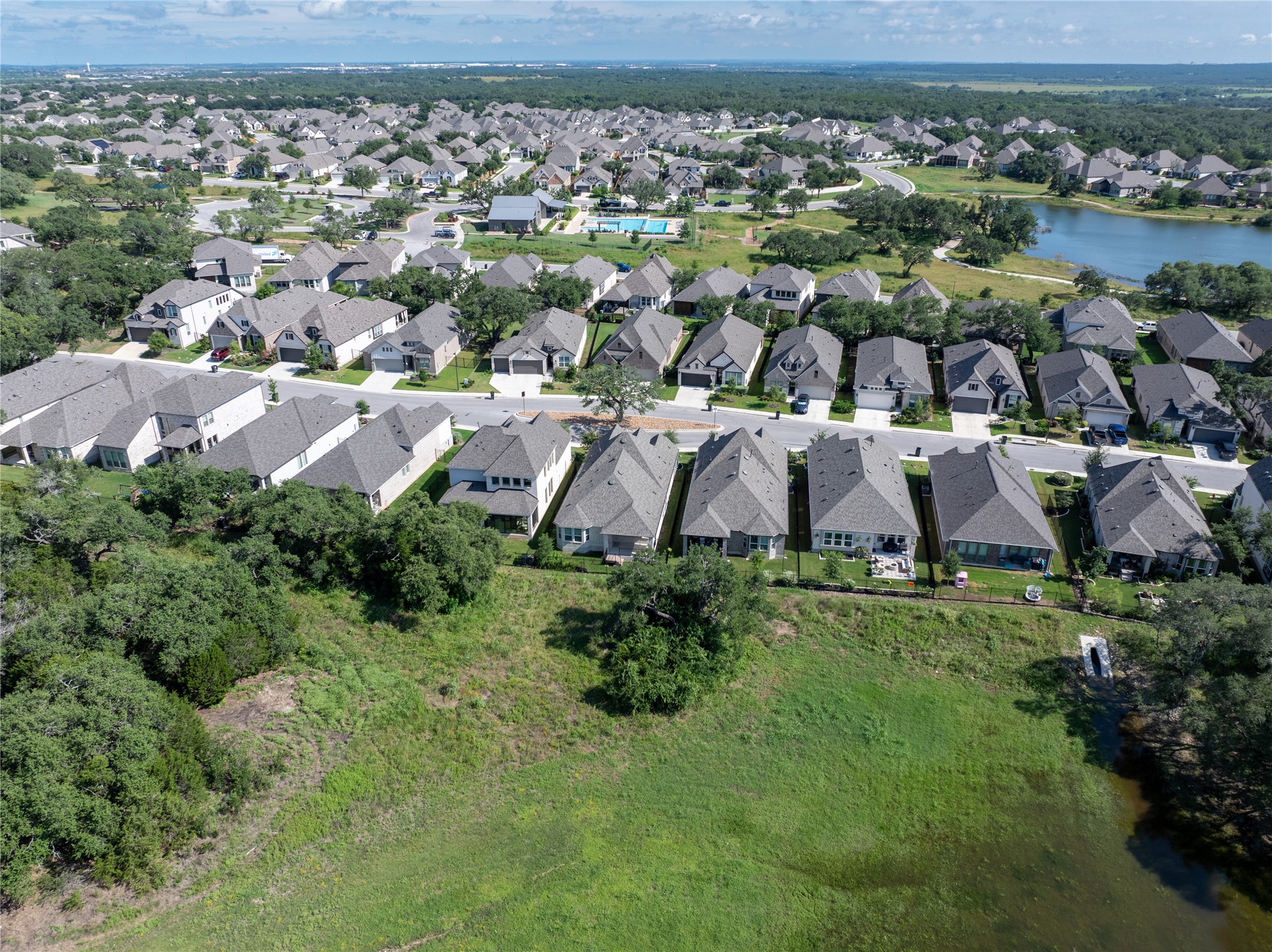 294 Kimble Creek Loop Kyle, TX 78640 - Photo 36 of 40 An aerial perspective reveals a vibrant neighborhood bordered by a tranquil lake.