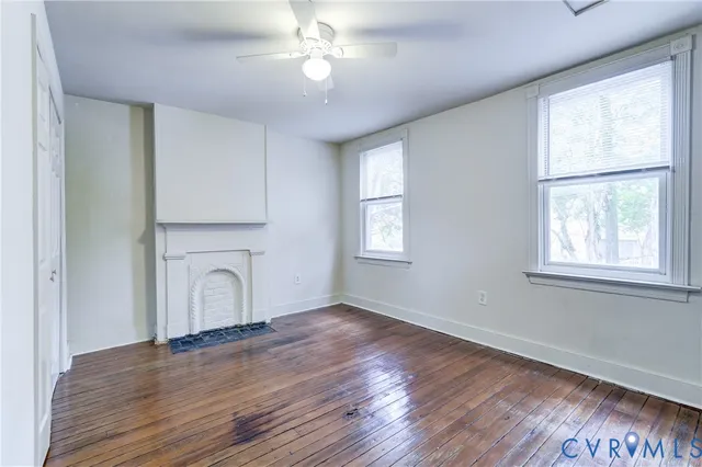 an empty room with wooden floor chandelier and windows