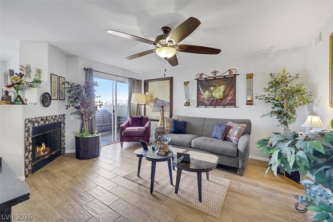 A living area features a corner fireplace with decorative tile, wood-look flooring, and a sliding glass door leading to a balcony.