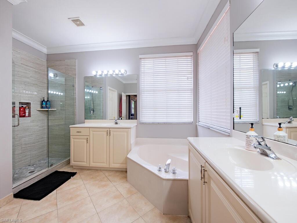 2346 Butterfly Palm Drive Naples, FL 34119 - Photo 16 of 45 Full bath with a shower stall, ornamental molding, light tile patterned flooring, a bath, and two vanities