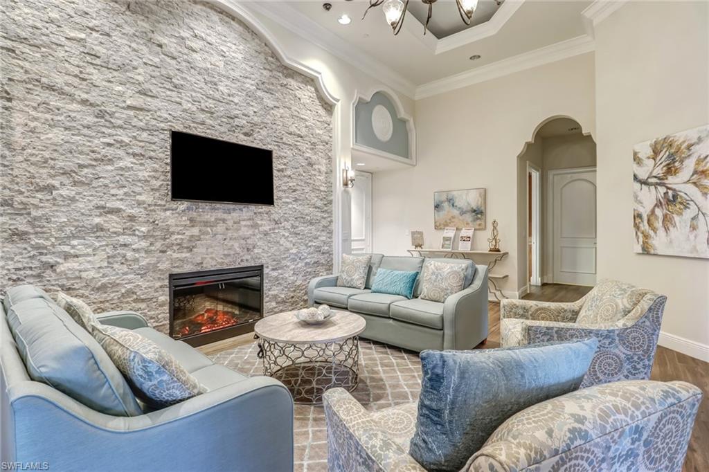 2346 Butterfly Palm Drive Naples, FL 34119 - Photo 25 of 45 Living room with a stone fireplace, wood finished floors, arched walkways, a towering ceiling, and crown molding