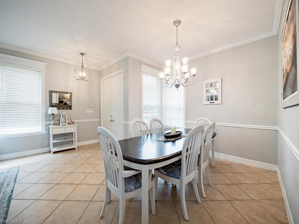 2346 Butterfly Palm Drive Naples, FL 34119 - Photo 7 of 45 Dining area with light tile patterned floors, a chandelier, and ornamental molding