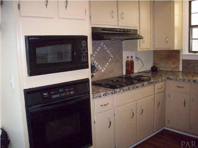 3900 Macks Road Century, FL 32535 - Photo 8 of 24 a kitchen with granite countertop white cabinets and black appliances