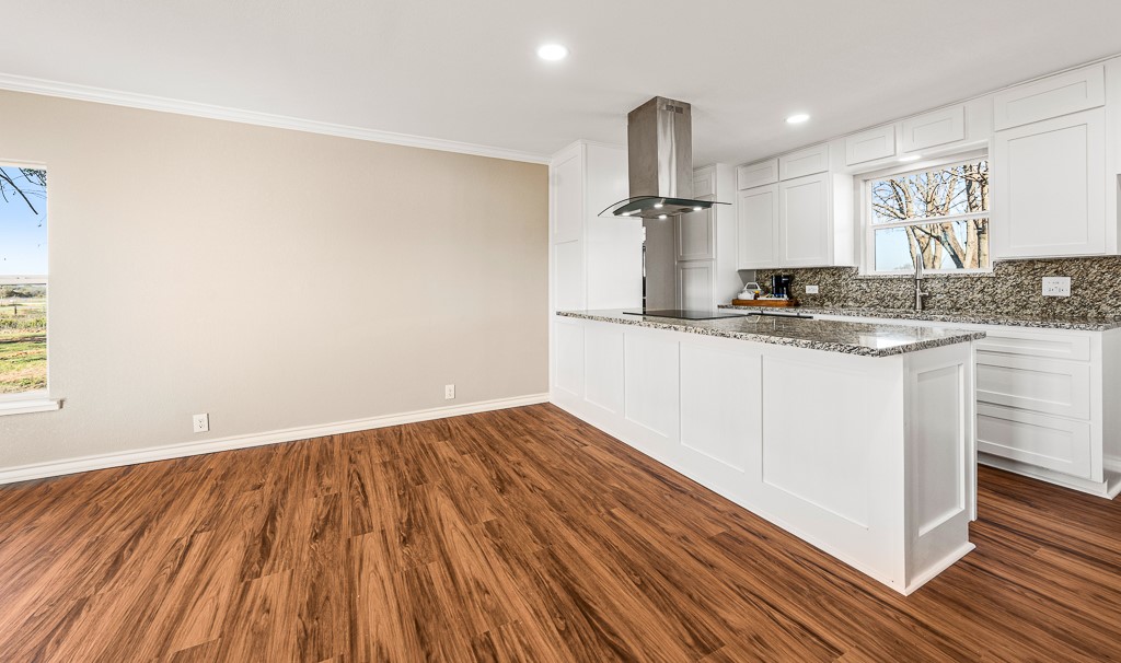 8896 Gholson Road Waco, TX 76705 - Photo 8 of 58 a kitchen with granite countertop wooden floors and white walls